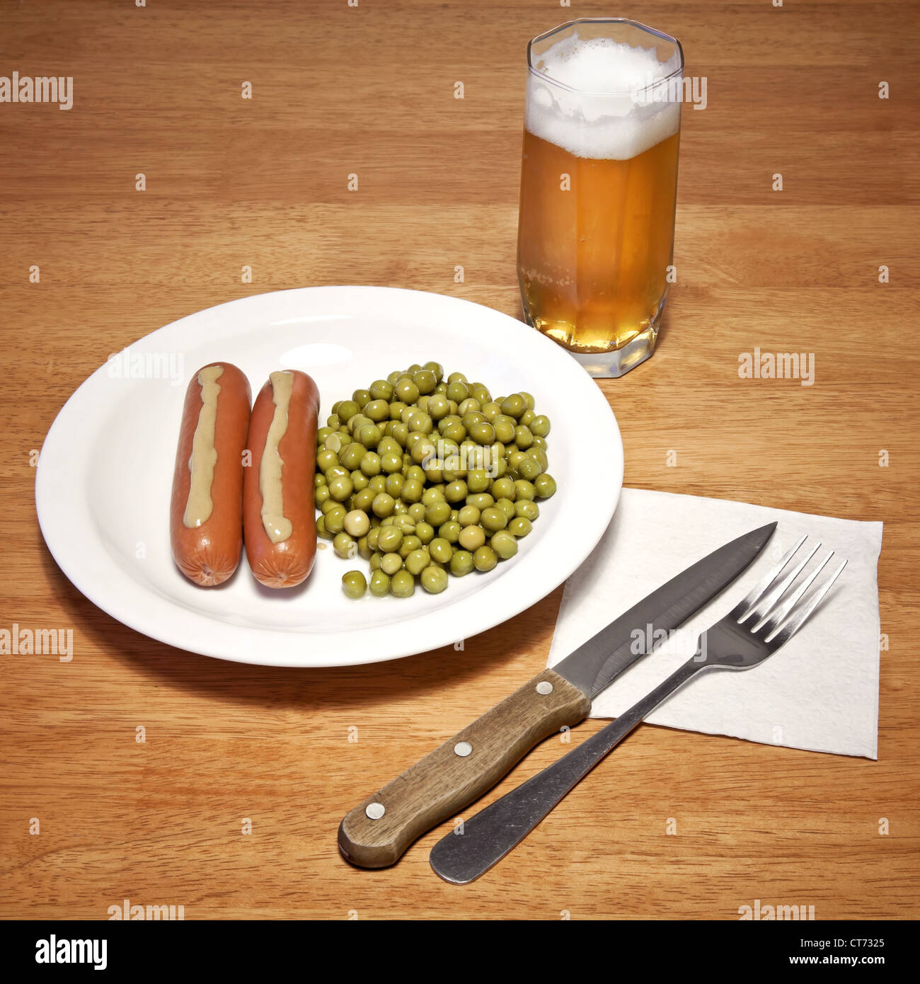 Thème de l'alimentation quotidienne. Les saucisses avec de la moutarde, pois verts et verre de bière sur la table en bois Banque D'Images