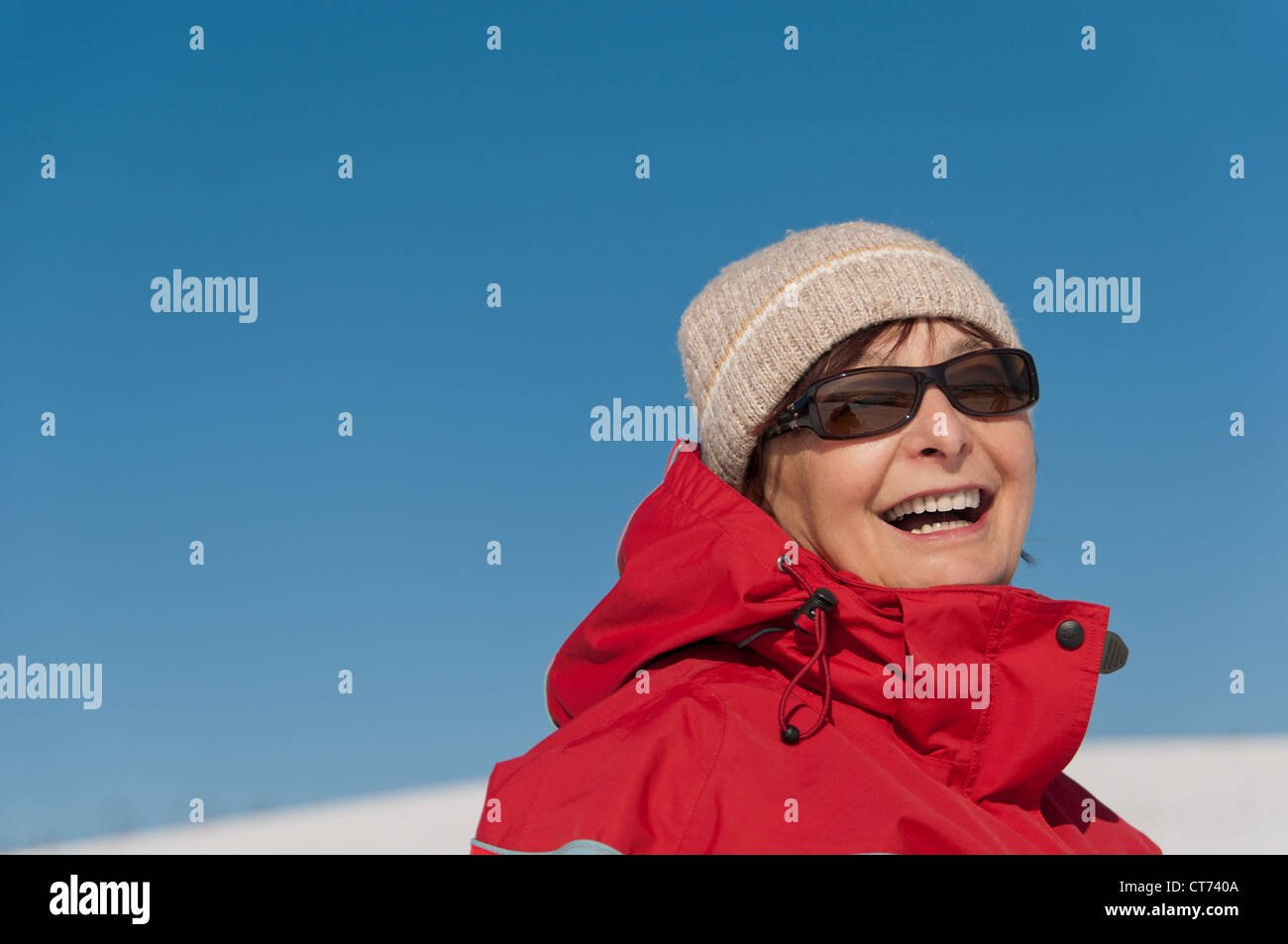 Portrait of smiling senior woman in winter - Ciel bleu en arrière-plan Banque D'Images