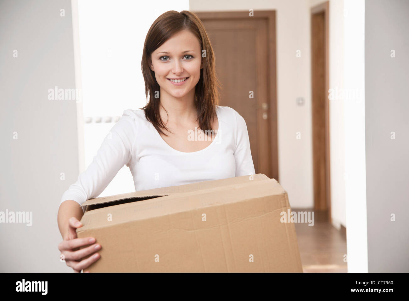 Portrait of young woman carrying moving box Banque D'Images