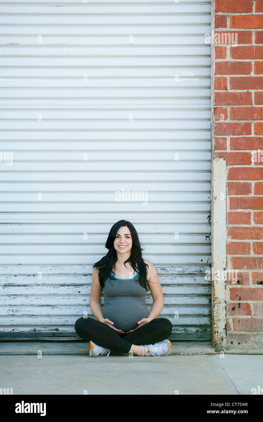 Jeune femme enceinte sitting cross legged, portrait Banque D'Images