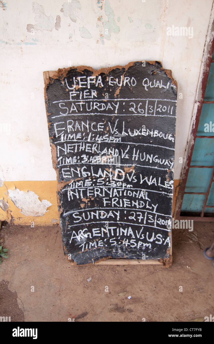 Pancarte mettant en valeur les jeux de football qui sont joués sur le village local de la télévision sur la soirée à venir à Migori, Kenya. Banque D'Images