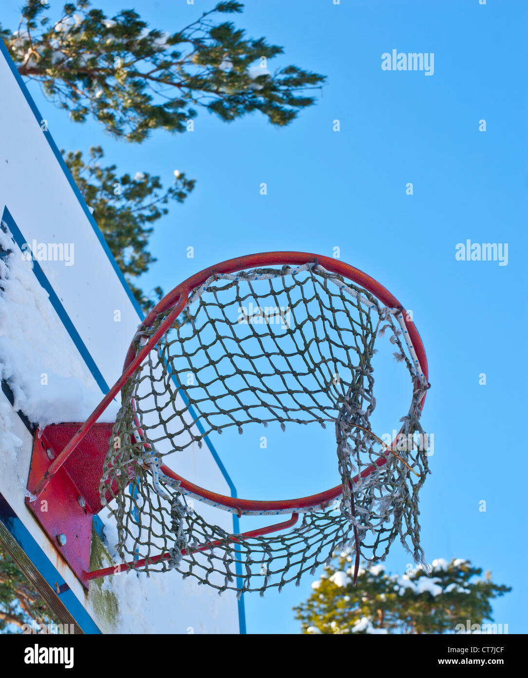 Anneau de basket avec un filet déchiré partiellement et un ciel bleu en arrière-plan Banque D'Images