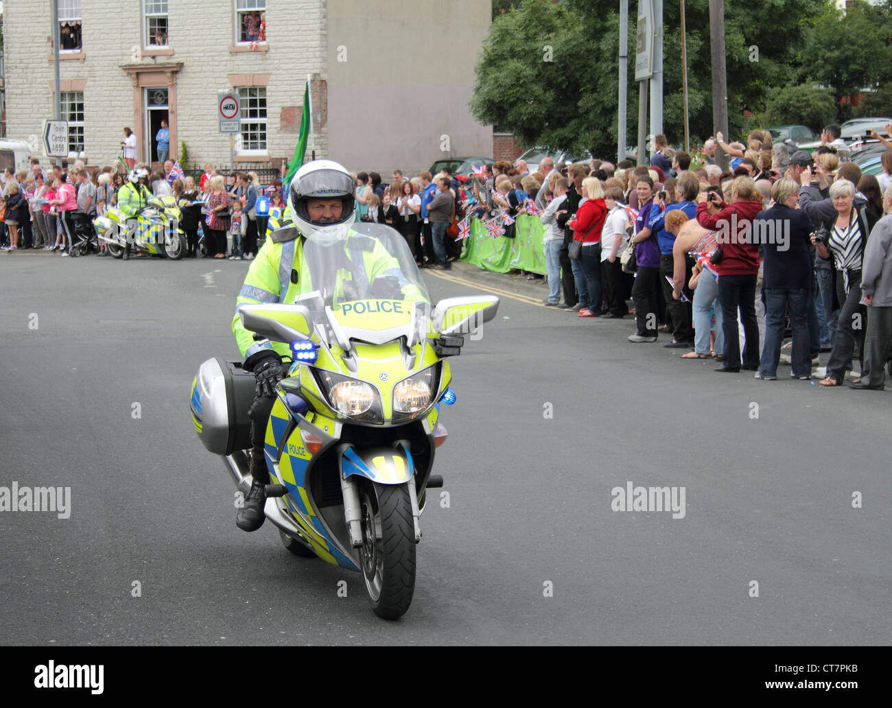 Une moto de police britannique précurseur et des foules de gens Banque D'Images