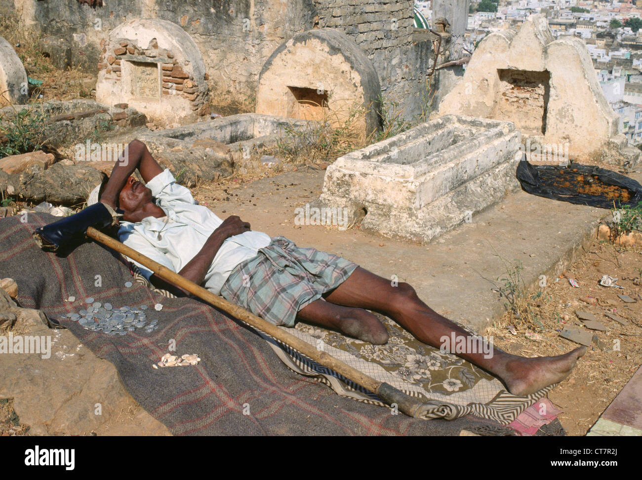 L'homme musulman amputé allongé sur le sol. Il est mendiant dans un cimetière (Inde) Banque D'Images