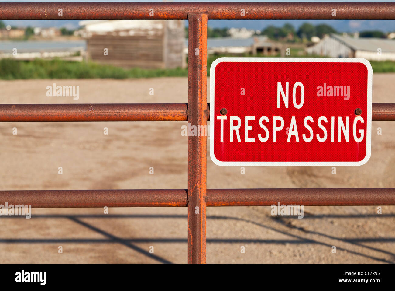 Rouge aucun signe d'intrusion sur une grille de fer du flou bâtiment de ferme derrière Banque D'Images