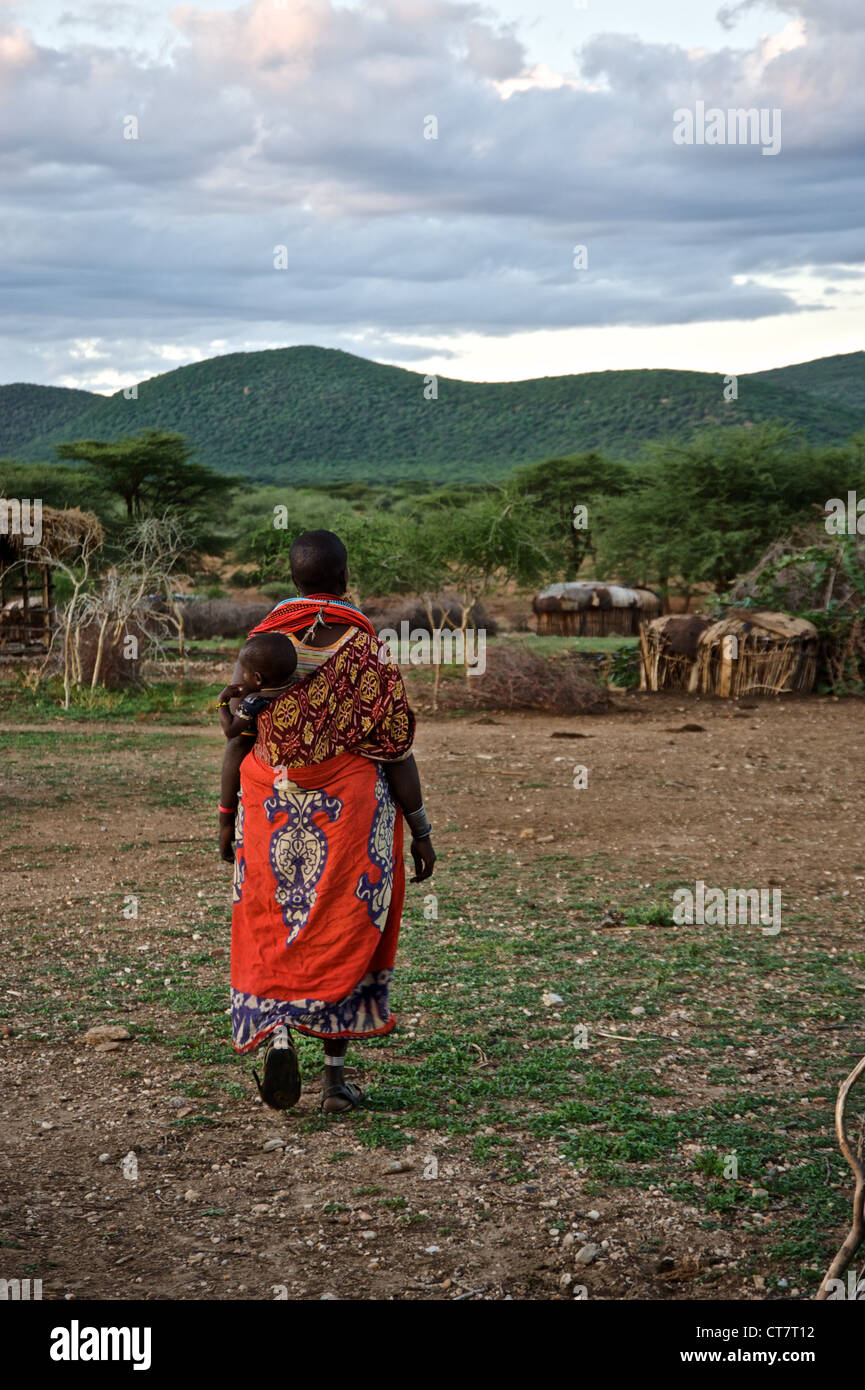 Woman walking trough village avec son enfant sur le dos. Samburu, Afrique. Banque D'Images