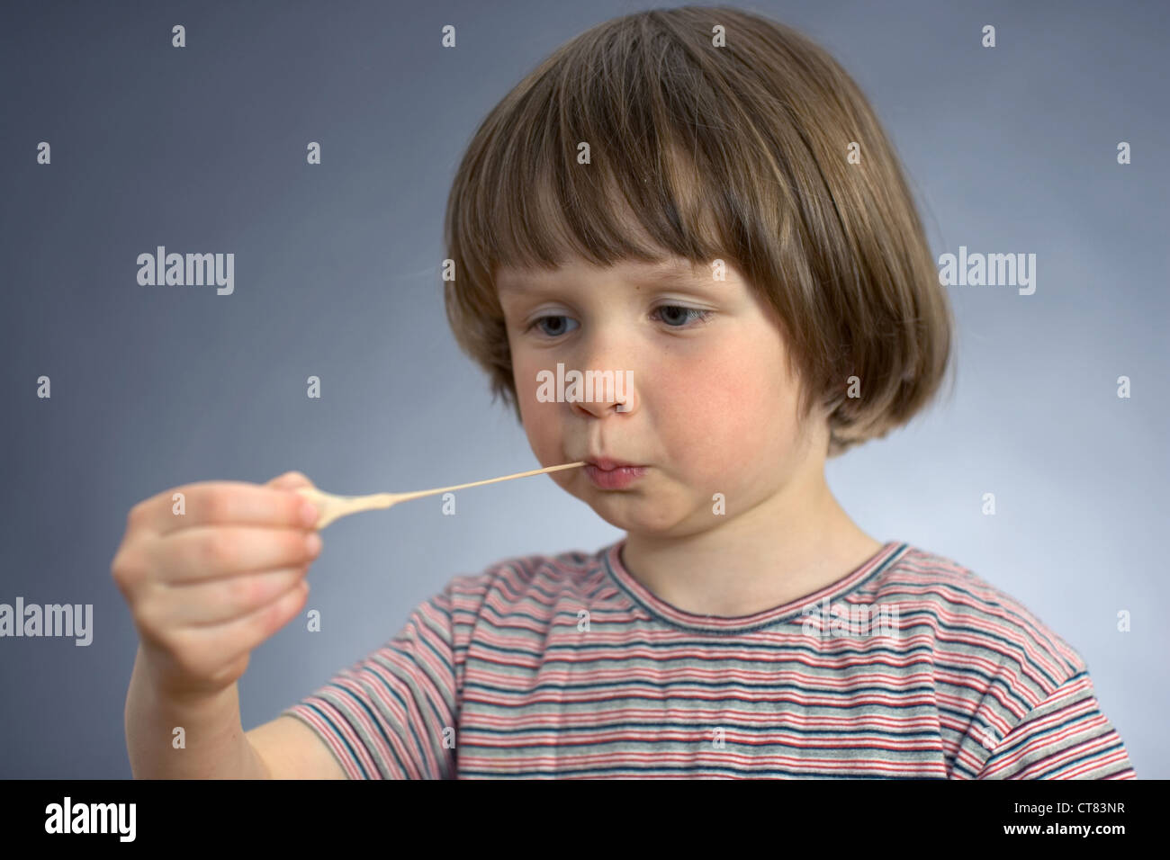 Un enfant tire un morceau de gomme hors de sa bouche Banque D'Images