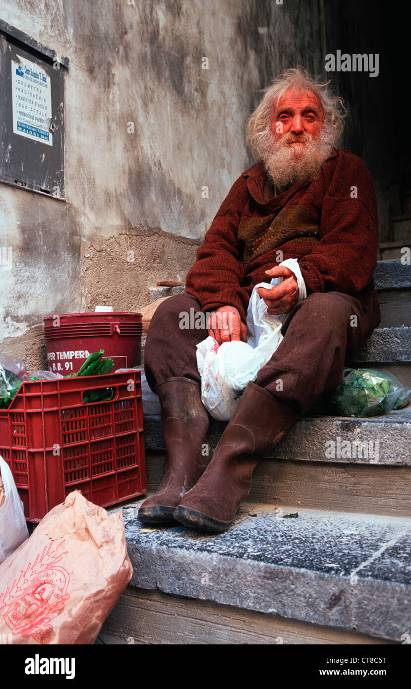 Vieil homme avec une barbe assis sur un escalier Banque D'Images
