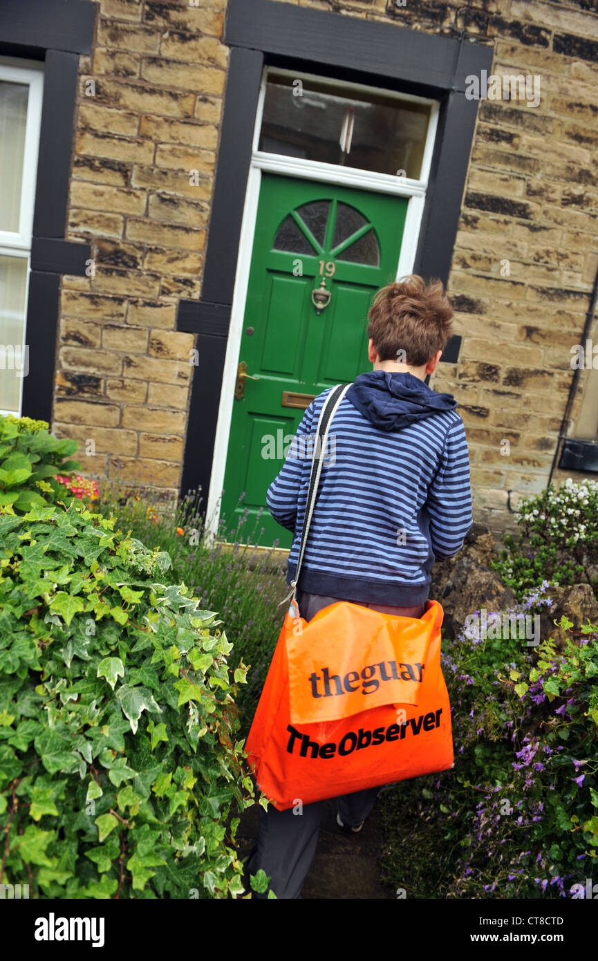 Un garçon de papier journaux offre aux maisons, premier emploi, Yorkshire du Nord. Banque D'Images