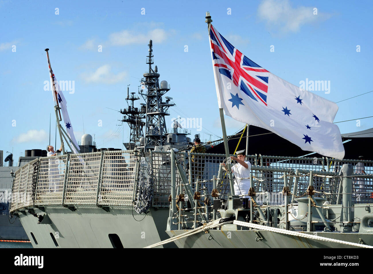 Les marins australiens élèvent les couleurs à bord de la frégate de missiles guidés de classe Adélaïde HMAS Darwin (FFG 04) et de la frégate de classe Anzac de la Marine royale australienne HMAS Perth (FFH 157) pendant la Rim of the Pacific (RIMPAC) 2012. Vingt-deux nations, 42 navires, six sous-marins, plus de 200 avions et 25,000 membres du personnel participeront à l'exercice biennal Rim of the Pacific (RIMPAC) 2012 prévu du 29 juin au 3 août, dans et autour des îles hawaïennes. RIMPAC est le plus grand exercice maritime international au monde Banque D'Images