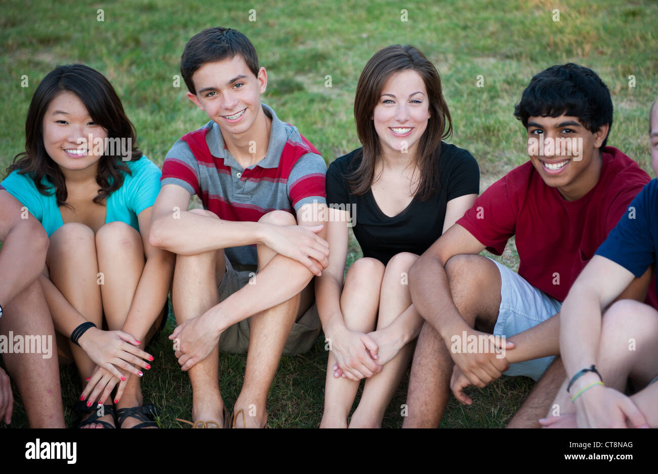 Groupe d'adolescents heureux divers assis dehors Banque D'Images