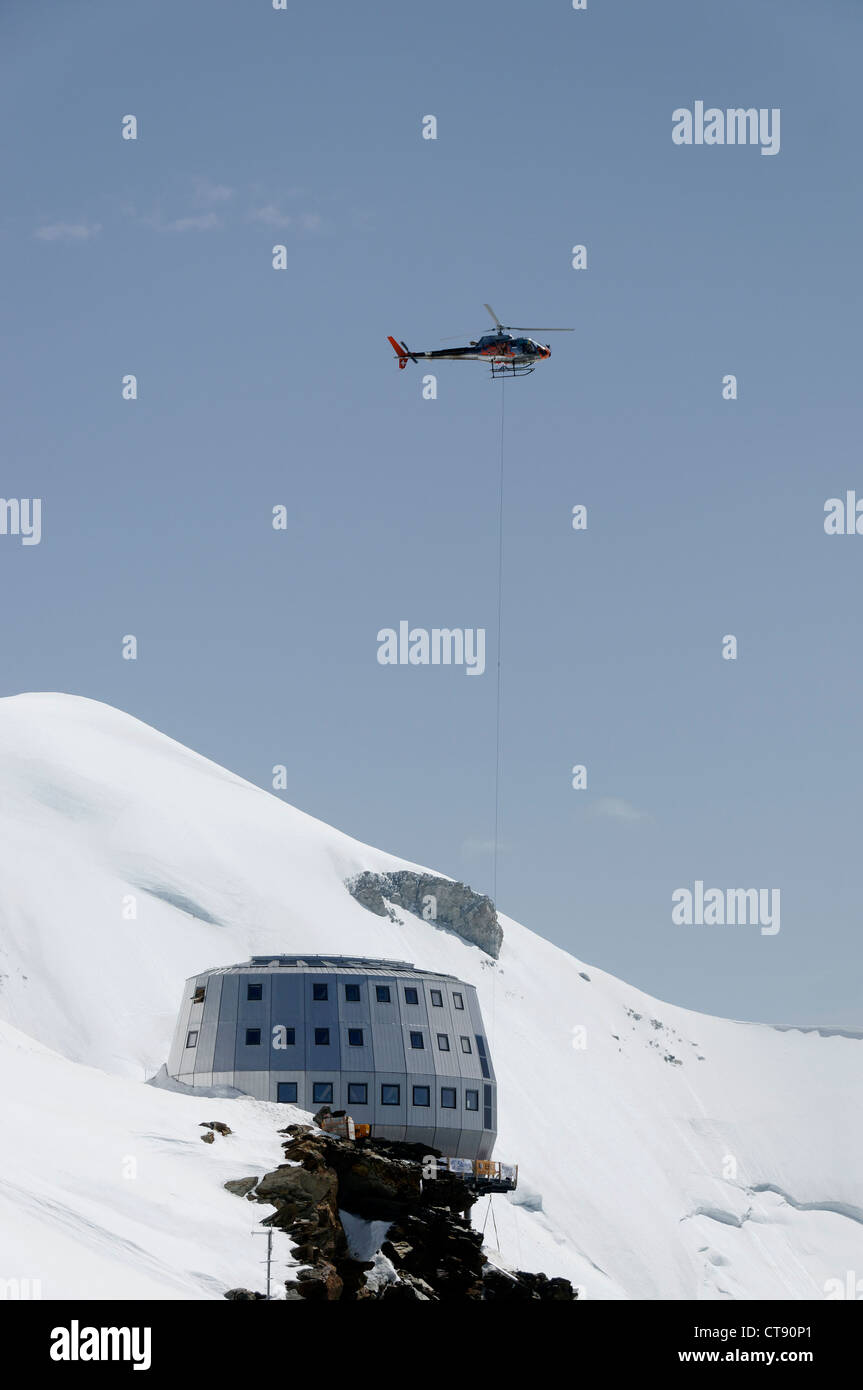 La chute d'un hélicoptère d'une charge à une nouvelle cabane chantier dans les alpes Banque D'Images