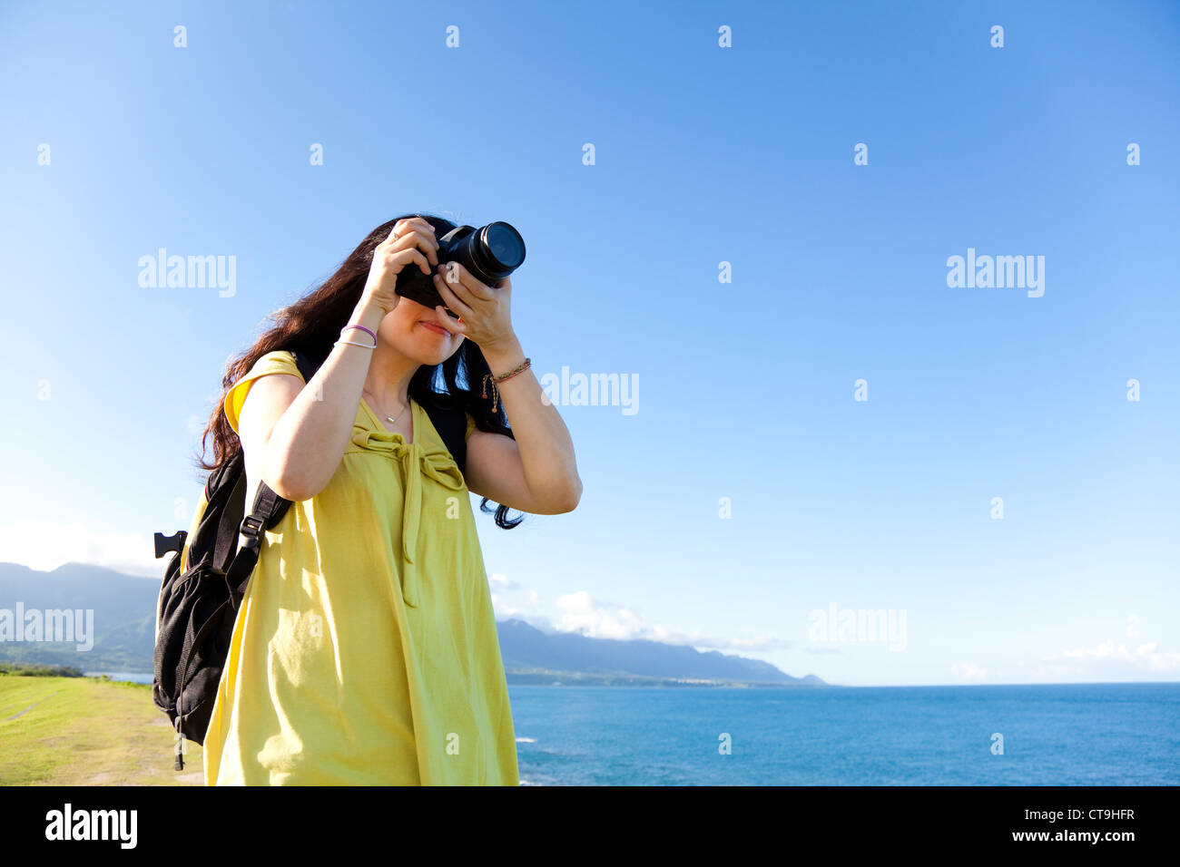 Jeune femme avec sac à dos, debout sur la colline taking photo Banque D'Images