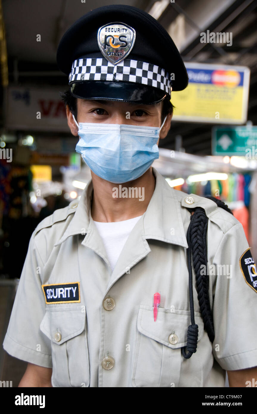 Un agent de sécurité portant son masque de visage dans une rue de vapeurs du trafic à Bangkok, Thaïlande Banque D'Images