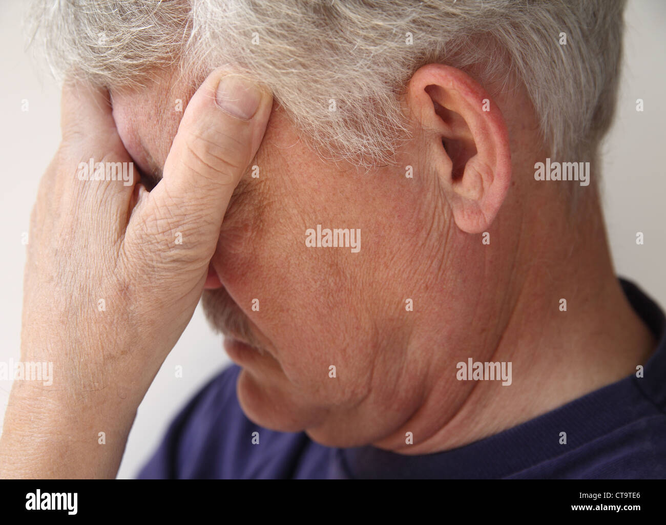 Un homme plus âgé couvre ses yeux alors qu'il est submergé par l'émotion ou la dépression Banque D'Images