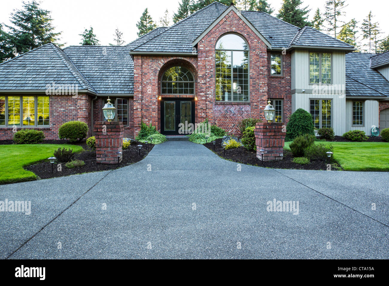 Vue avant du grand cèdre et brique chambre avec plein d'arbres cultivés et le ciel en arrière-plan Banque D'Images