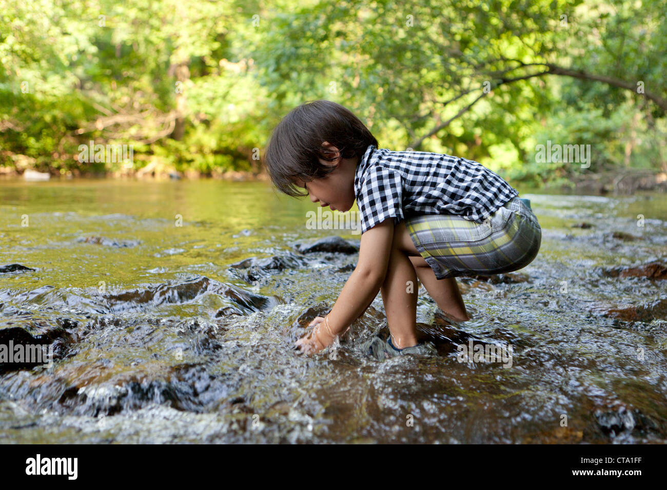 Un garçon jouant dans un ruisseau peu profond - USA Banque D'Images