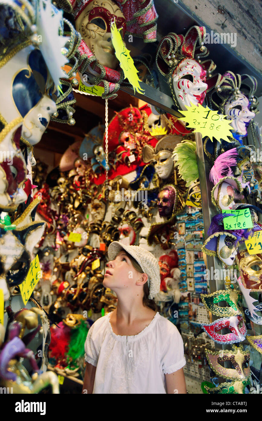 Fille, 12 ans, en face d'un masque de Venise boutique, Venise, Vénétie, Italie Banque D'Images