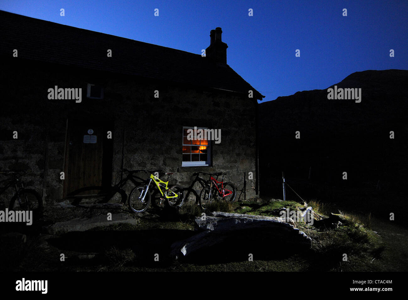 Deux vélos de montagne contre le mur d'un bothy dans les montagnes de l'Ecosse au crépuscule. Banque D'Images