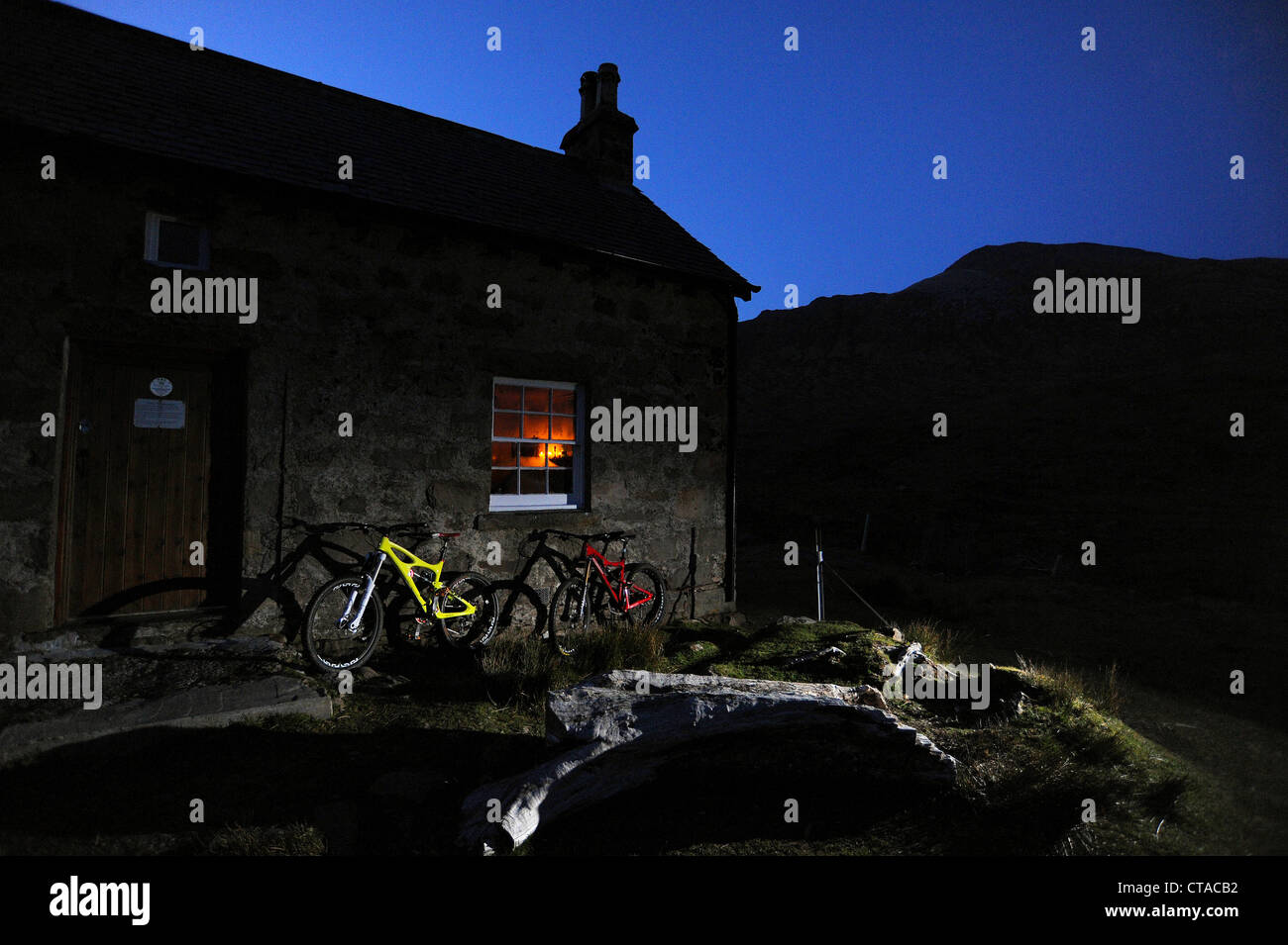 Deux vélos de montagne contre le mur d'un bothy dans les montagnes de l'Ecosse au crépuscule. Banque D'Images