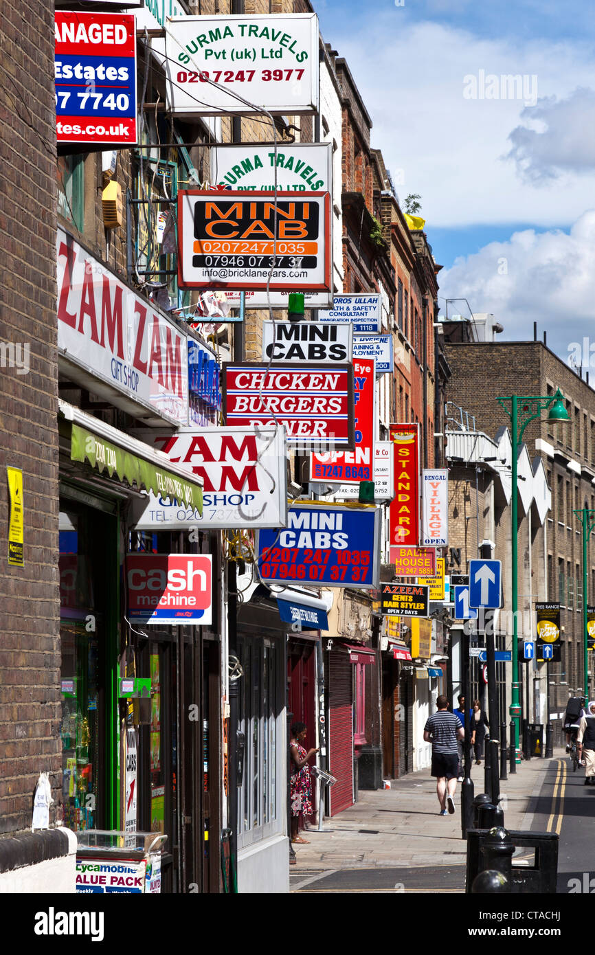 Les panneaux au-dessus des boutiques, emporter l'& Mini-cab Bureaux sur Brick Lane dans l'East End londonien Banque D'Images