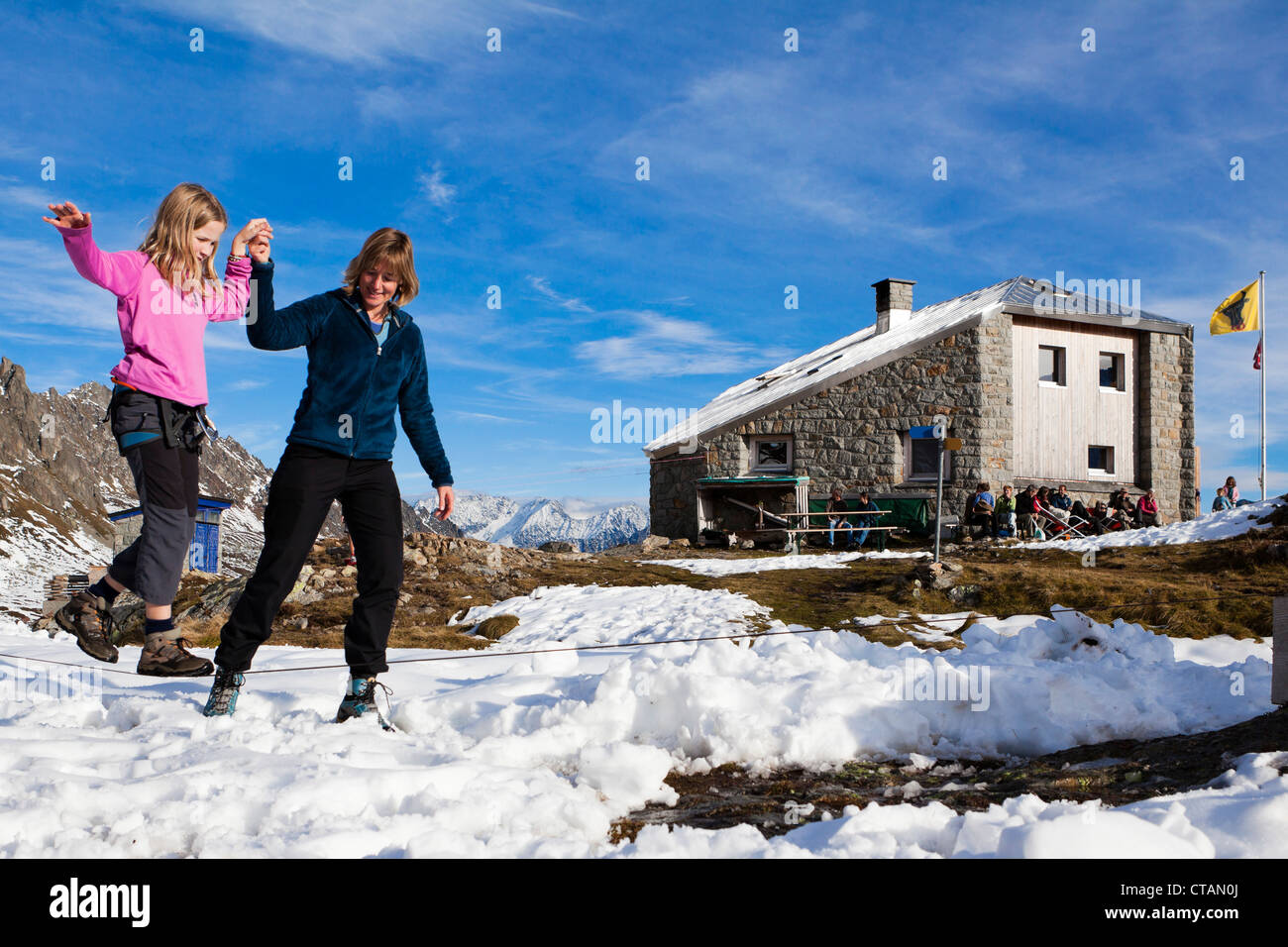 Une femme d'aider une jeune fille en équilibre sur un Sewenhut à la slackline, SAC Swiss Alpine-Club, Alpes Suisses, Kanton Uri, Suisse Banque D'Images