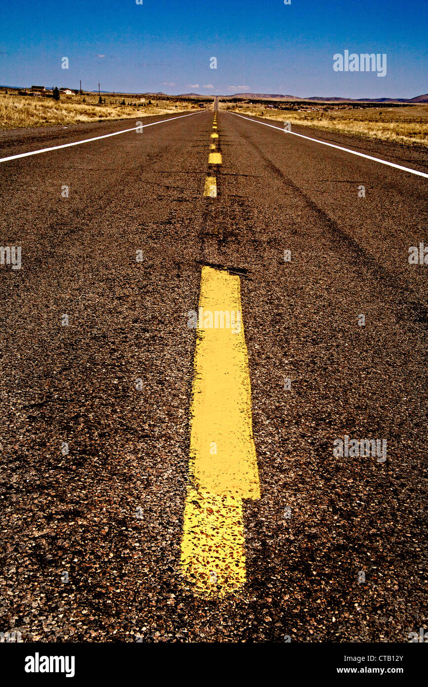 Une bande de circulation jaune divise une longue ligne droite de la route vide en Arizona. Banque D'Images