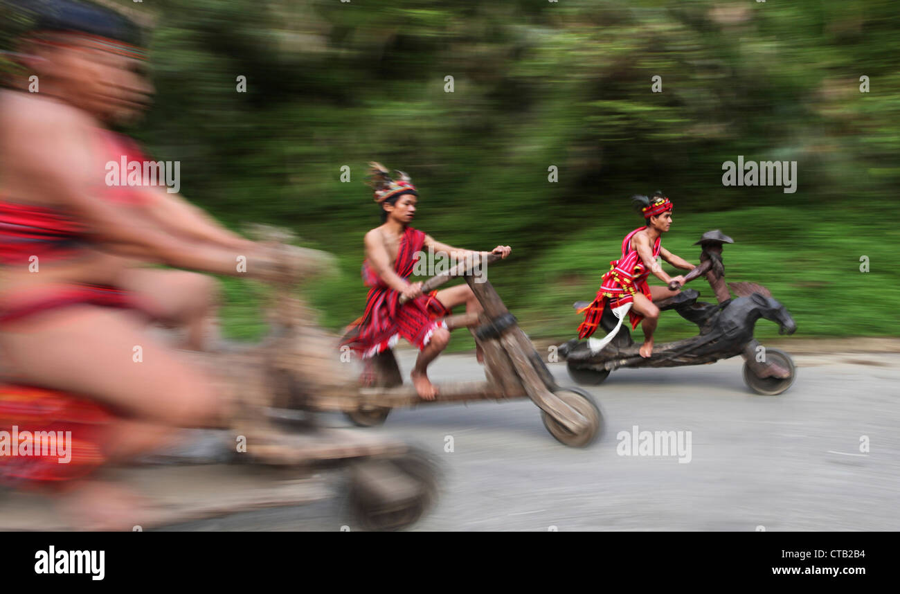 Les hommes d'Ifugao vitesse excessive sur les scooters en bois, Banaue, Ifugao, l'île de Luzon, Philippines Banque D'Images