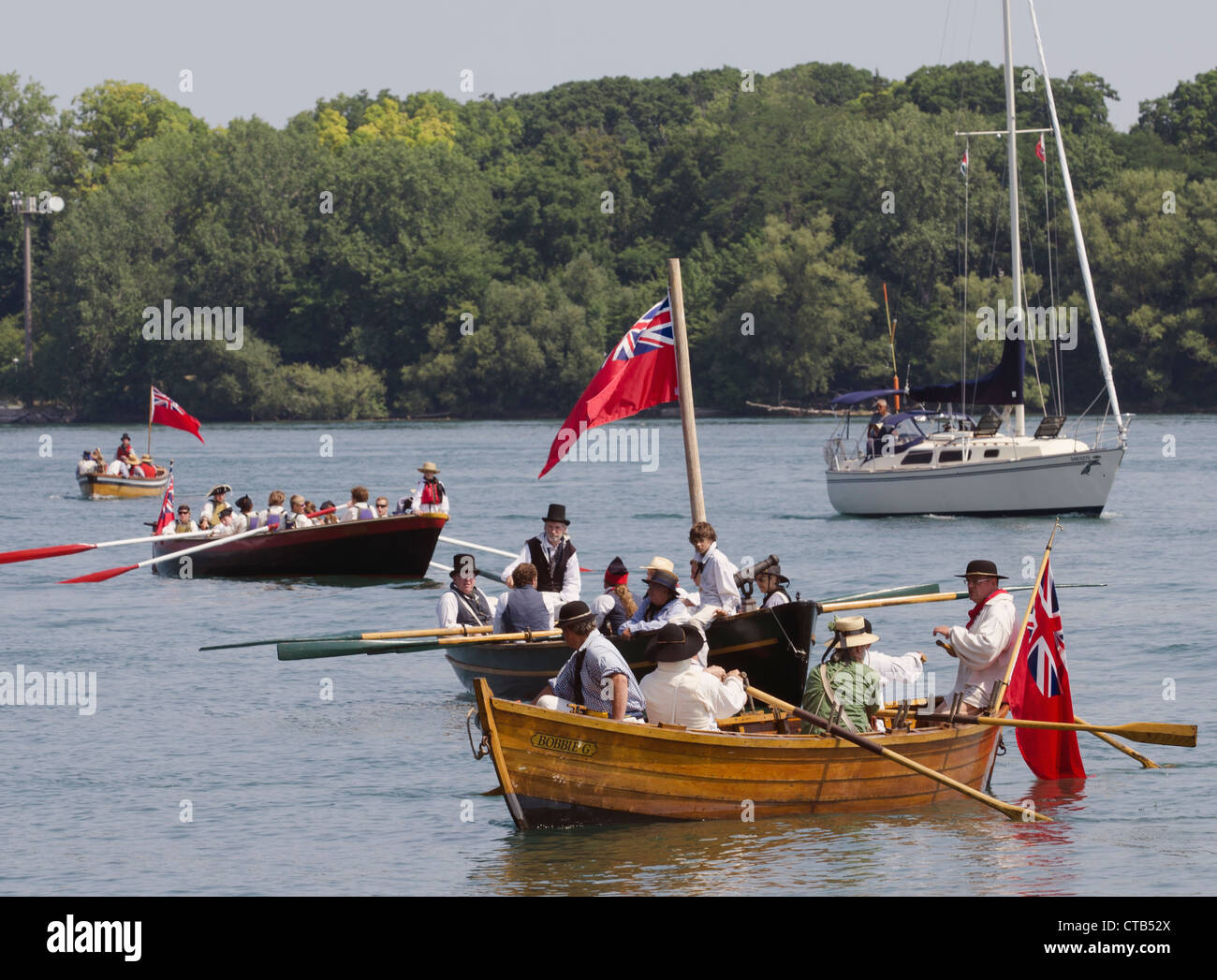 Certains de la manoevre bateau long sur la rivière Niagara, alors qu'un voilier croisières par en arrière-plan. Banque D'Images