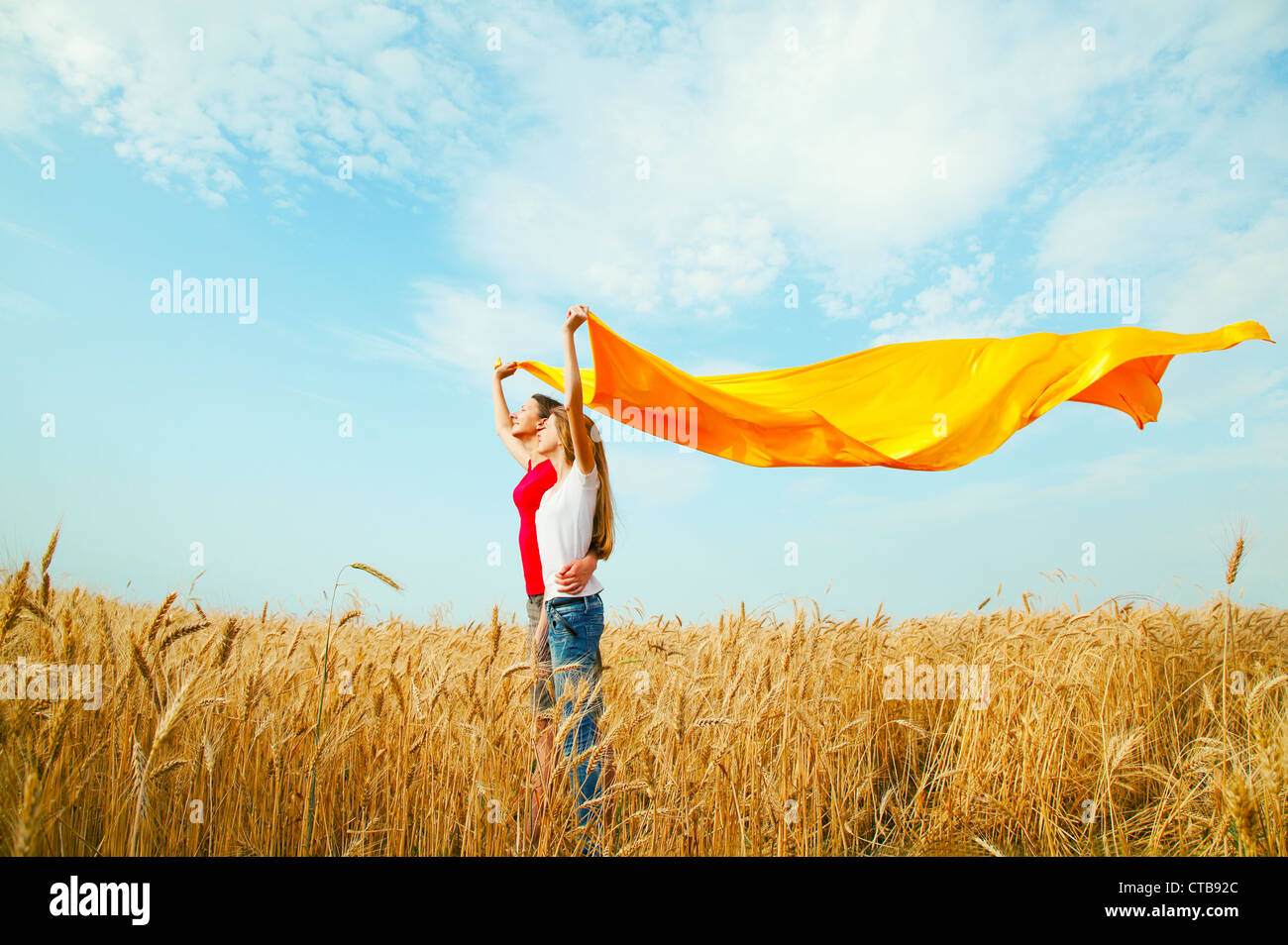 Les filles de l'adolescence à un champ de blé avec tissu jaune Banque D'Images