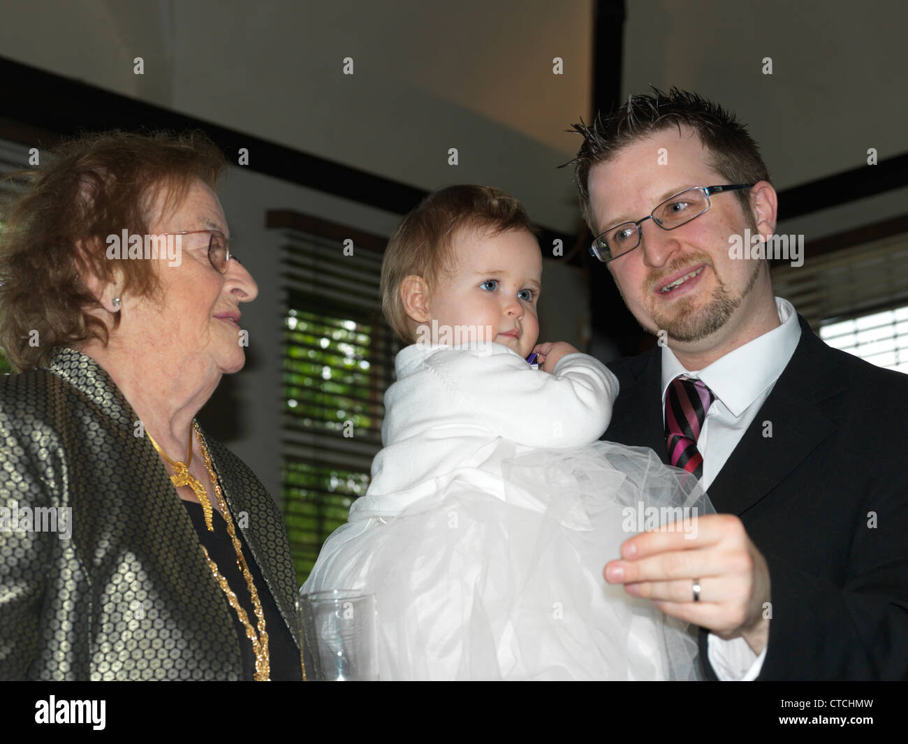 Grand-mère et père Holding Baby Girl après le baptême à la réception de baptême Banque D'Images