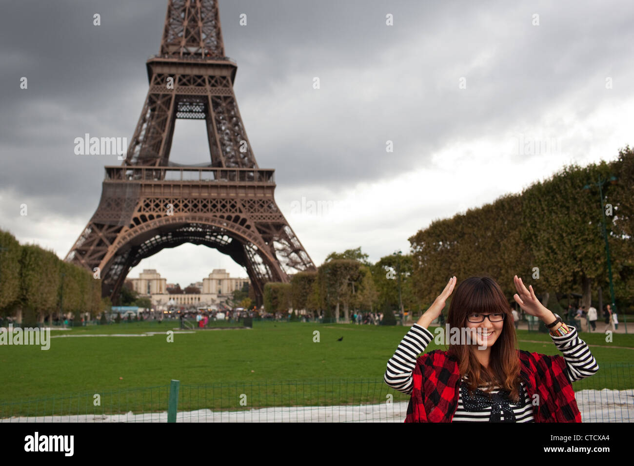 Un touriste chinois pose pour une photo devant la Tour Eiffel dans le parc du Champ de Marc - Champ de Mars, Tour Eiffel à Paris Banque D'Images