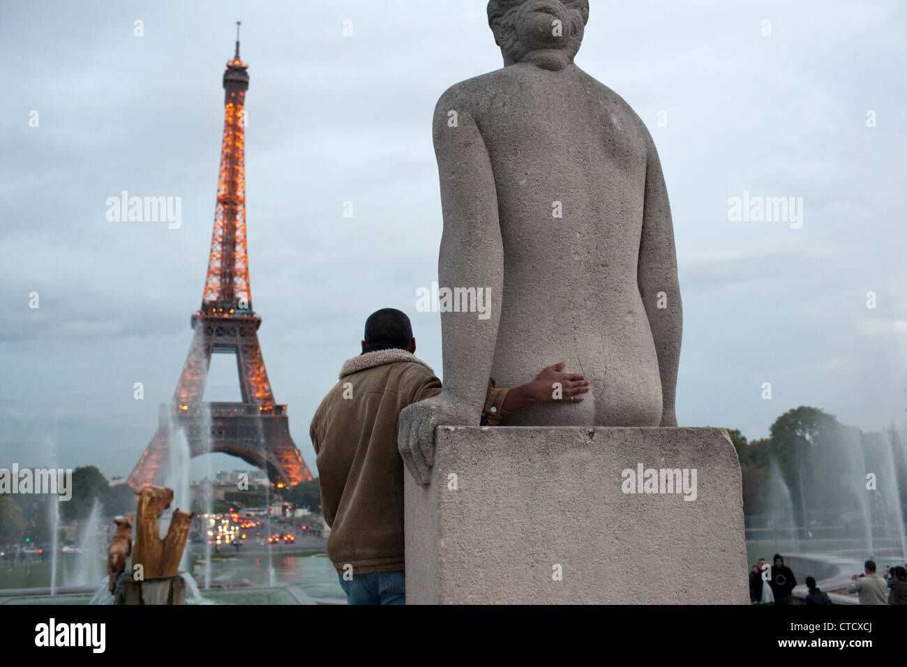 Une scène d'humour quand un homme pose pour une photo avec une statue au Trocadéro près de la Tour Eiffel à Paris, France. Banque D'Images