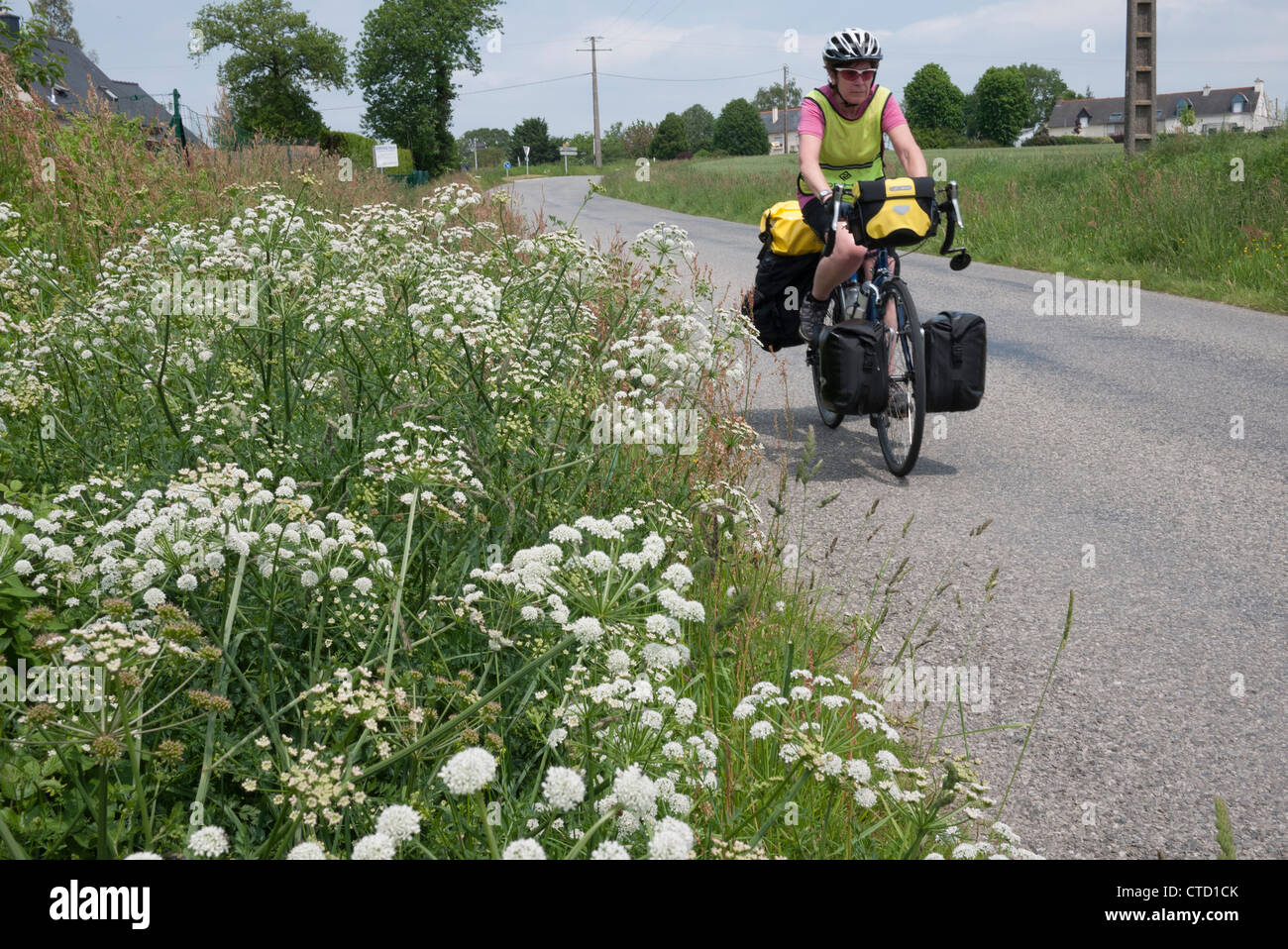 Dame vélo de randonnée le long d'une route française en Bretagne Banque D'Images