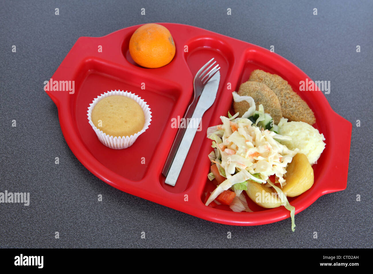 École saine déjeuner dîner servi sur le plateau en plastique rouge préformé, burger de haricots salade, muffin, orange Banque D'Images