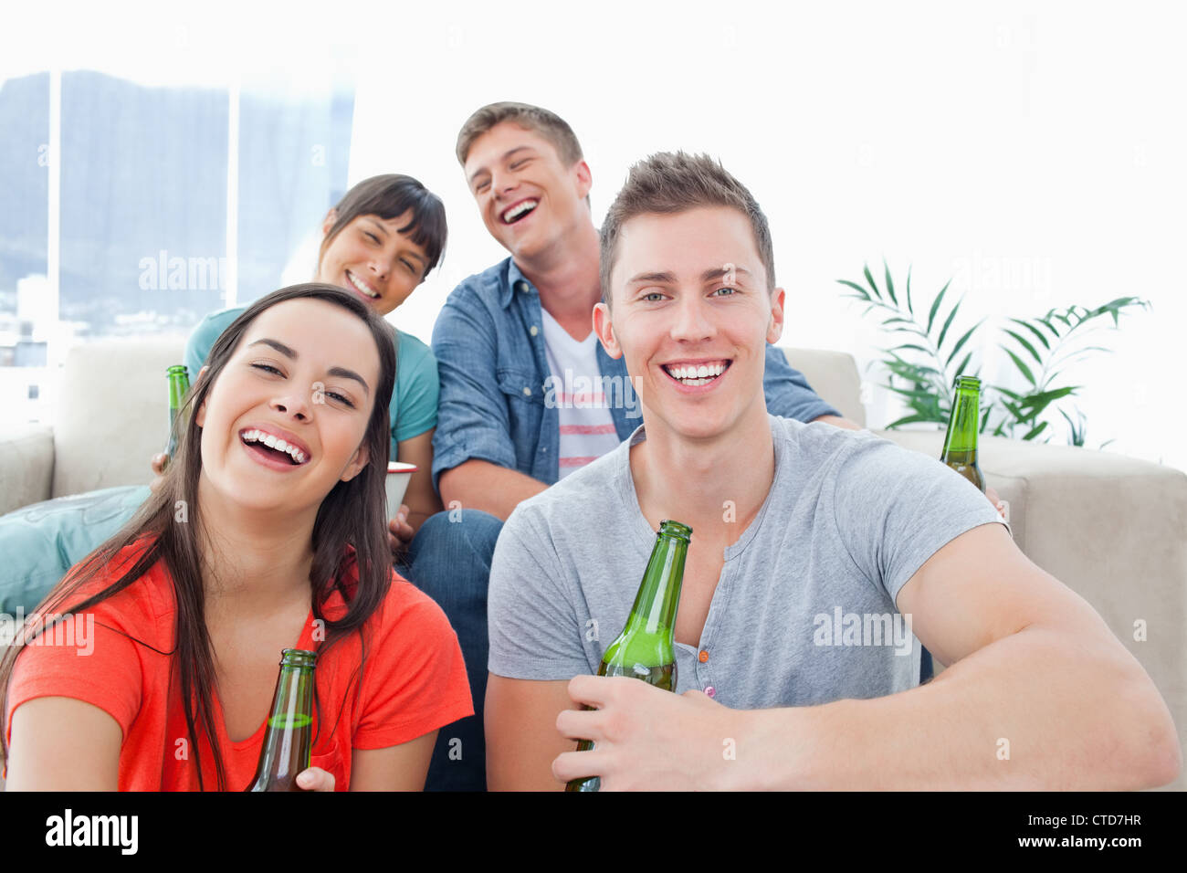 Quatre personnes dans un salon bénéficiant de la bière et de s'amuser ensemble Banque D'Images