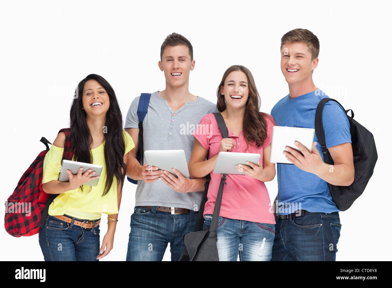 Un groupe d'étudiants avec les tablettes et les sacs à dos en souriant et regardant la caméra Banque D'Images