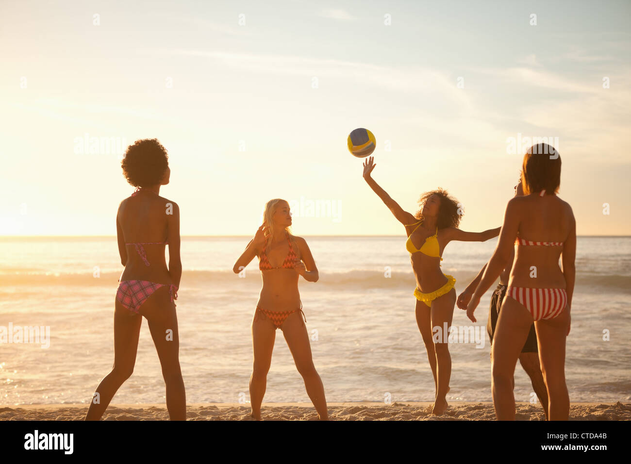 Les jeunes femmes jouant avec un ballon de plage en face de la mer Banque D'Images