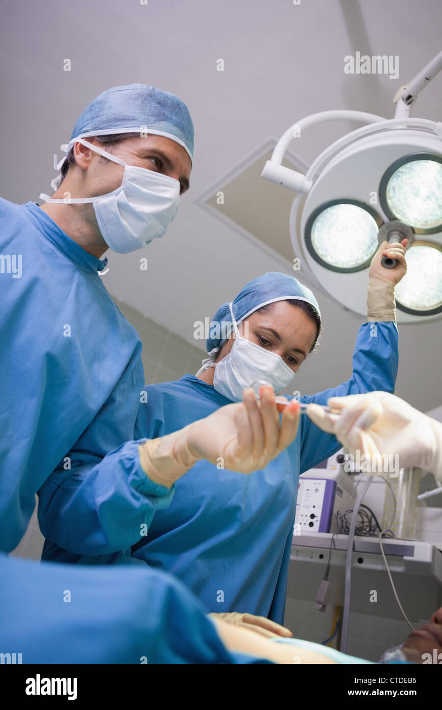 L'équipe chirurgicale chirurgie travaillant sous les feux Banque D'Images