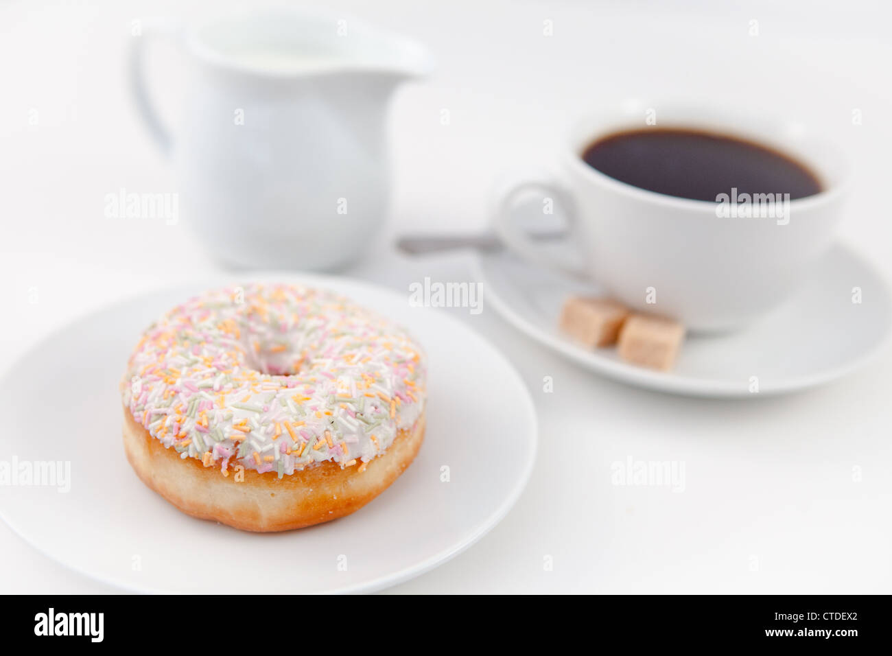 Lait Donut et une tasse de café sur les plaques blanches avec du sucre et cuillère Banque D'Images