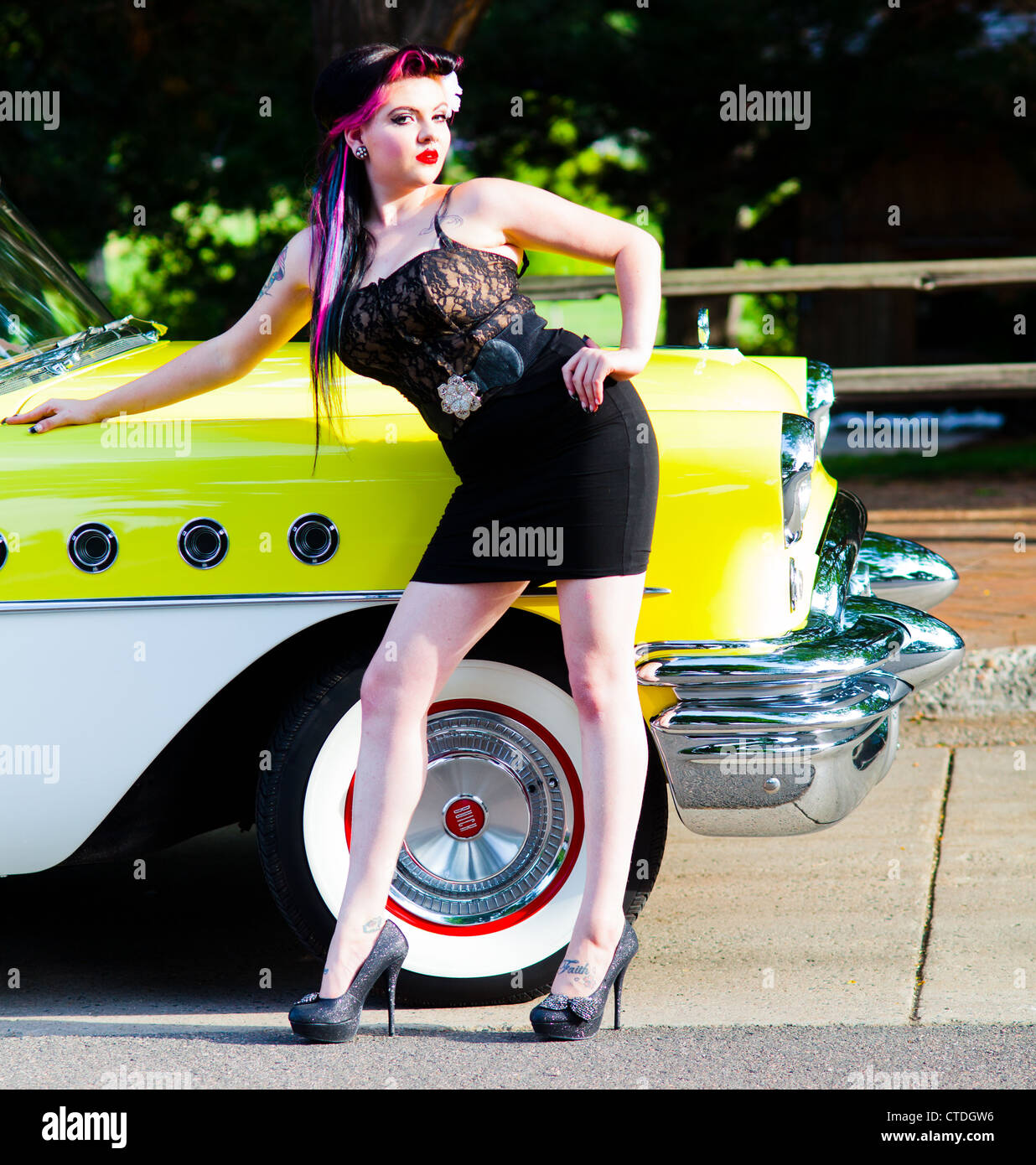 Femme femme habillée d'une façon rockabilly posant à côté d'un véhicule classique Banque D'Images