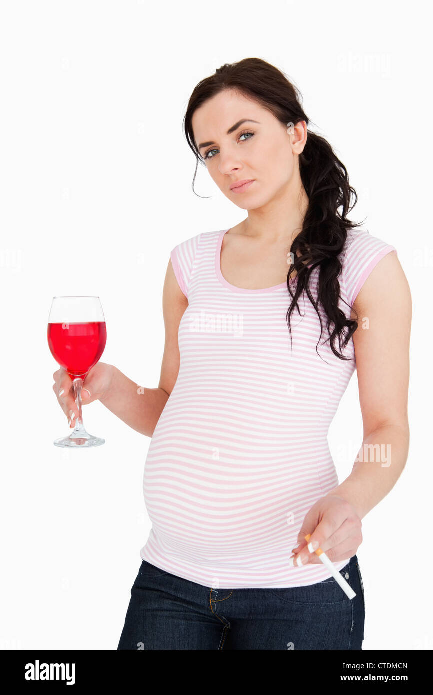 Pregnant brunette holding alcoholic drink and cigarette Banque D'Images