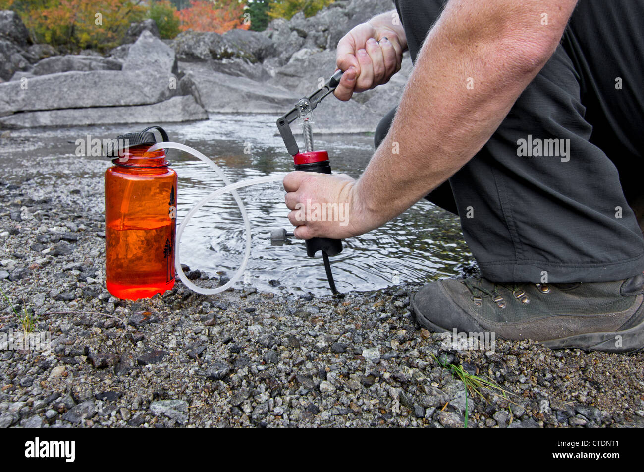 Une personne utilise un filtre à eau compact et léger pour pomper de l'eau potable Banque D'Images