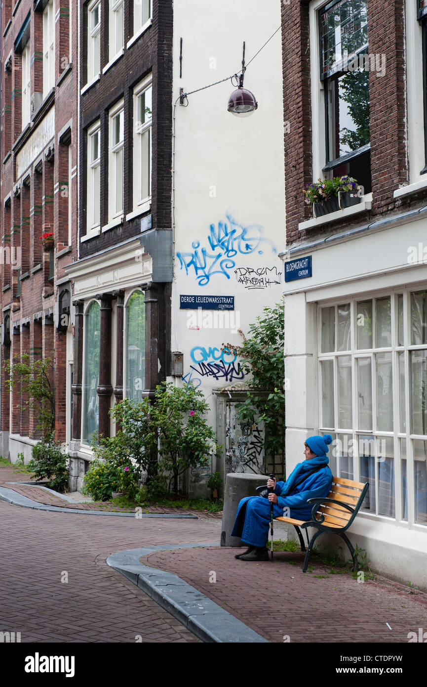 La normale des scènes de rue dans le quartier Jordaan d'Amsterdam. La femme en bleu assis sur l'Amstel. Banque D'Images