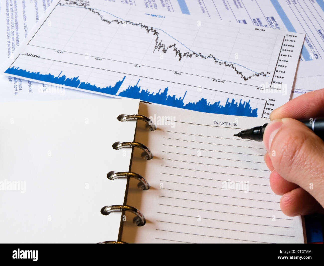 Libre d'un ordre du jour ouvert à une page de notes vierge. Un tableau d'analyse économique en baisse et d'histogramme dans l'arrière-plan. Banque D'Images