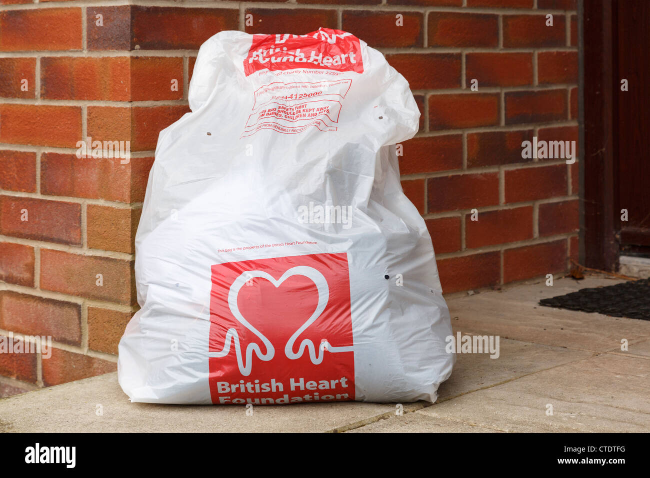 British Heart Foundation charity recyclage vêtements sac plein de vieux vêtements pour la collecte à l'extérieur d'une maison. Angleterre Royaume-uni Grande-Bretagne Banque D'Images