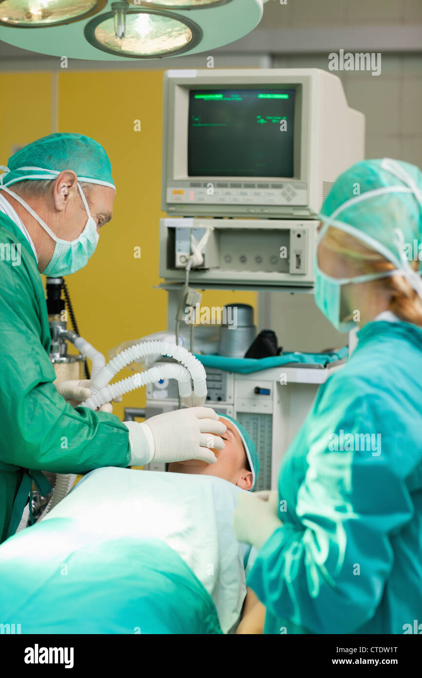 Patient allongé sur une table d'opération avec deux chirurgiens Banque D'Images