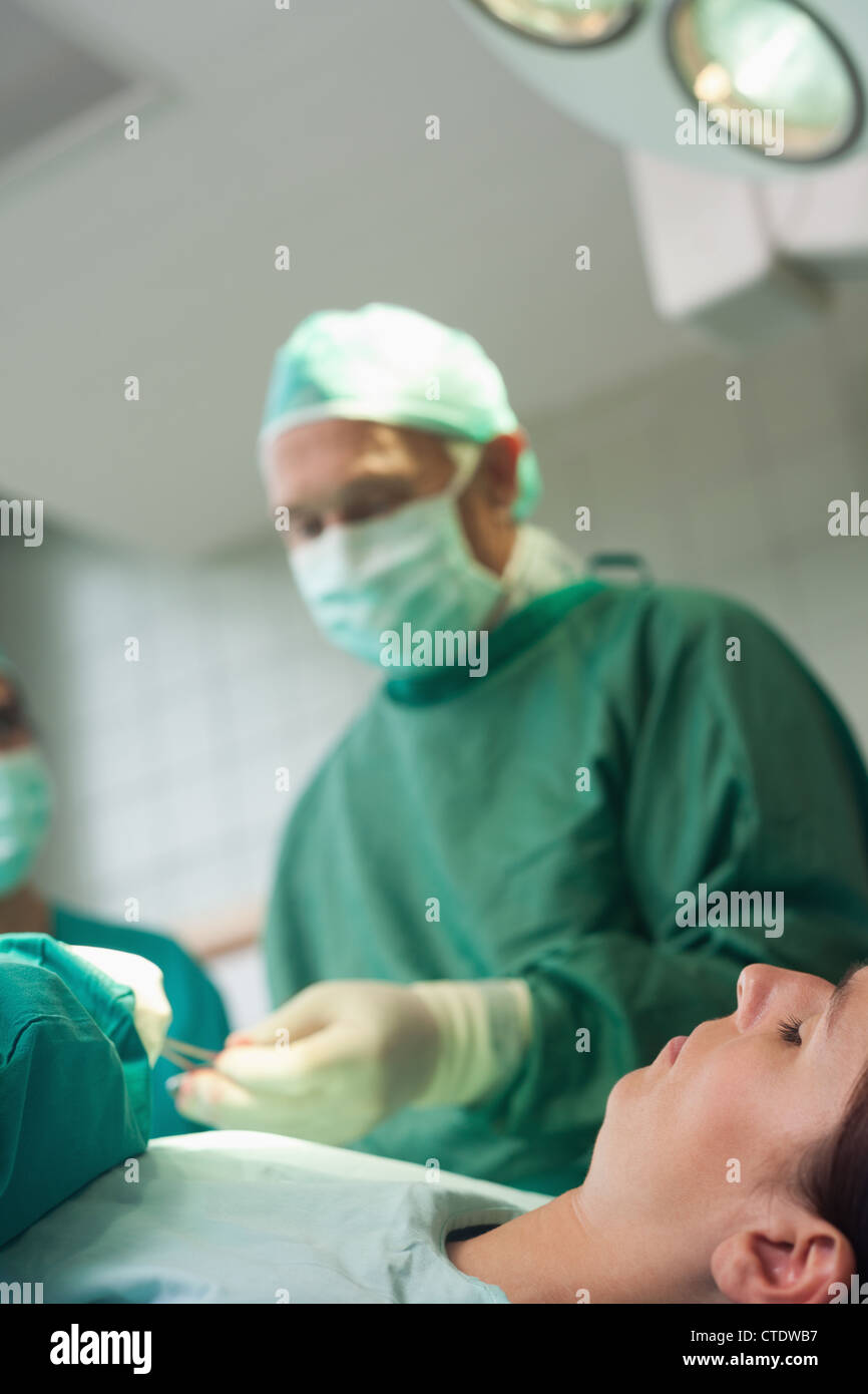 Patient dormir sur une table d'opération alors qu'un chirurgien est de prendre des ciseaux Banque D'Images