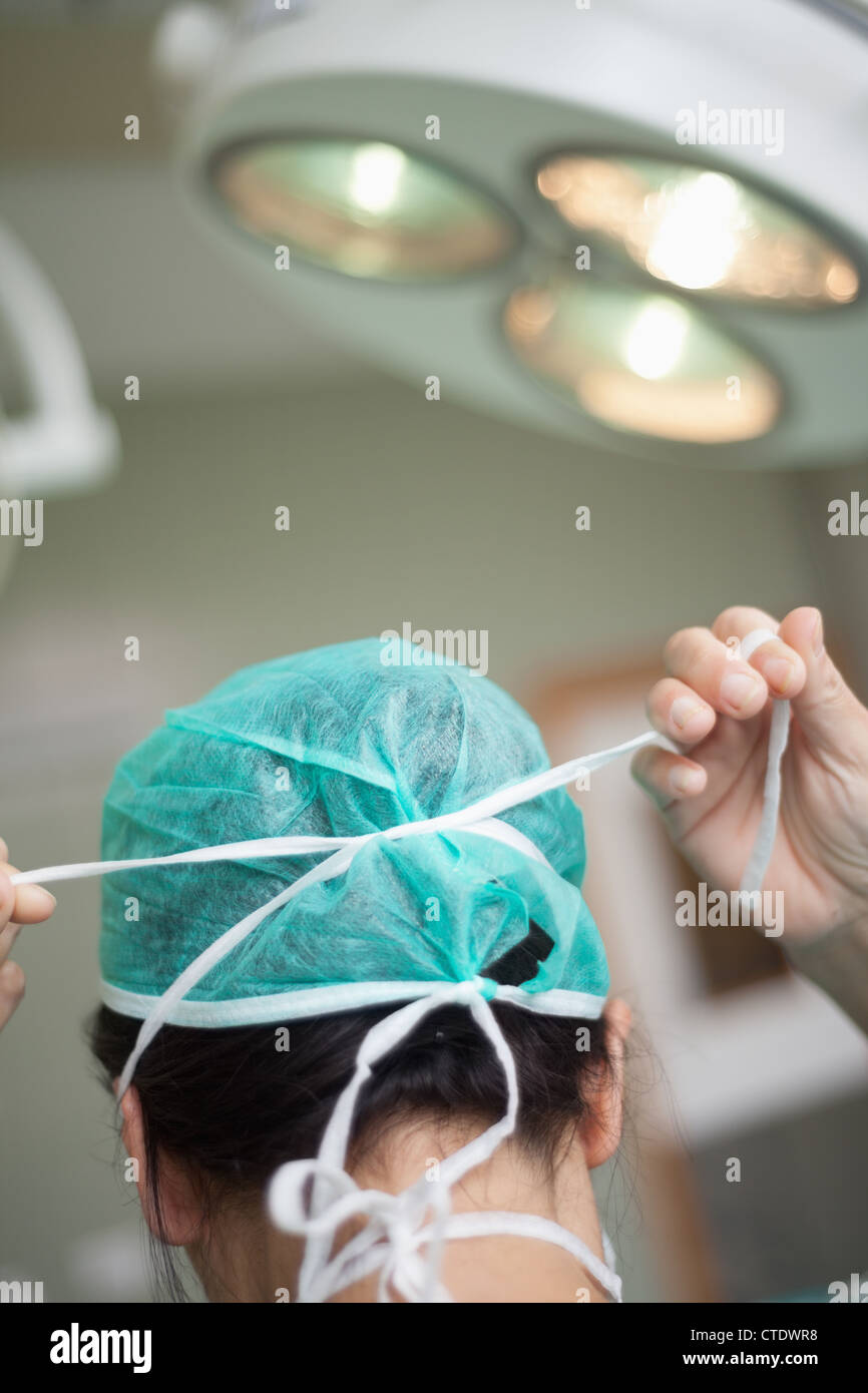 Femme chirurgien de mettre un chapeau sur la chirurgie Banque D'Images