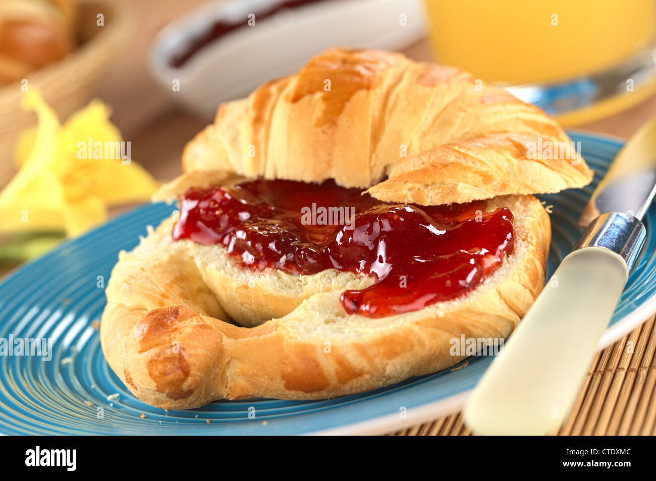 Un croissant au beurre et confiture de fraise (Selective Focus, Focus sur le grand morceau de fraise à l'avant) Banque D'Images
